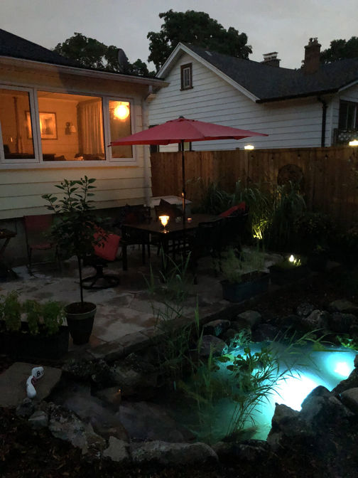 Random flagstone patio and a fish pond at night. Stone or paver patio project in London region by O'Connor Stone & Landscape, local landscape and hardscape contractor.
