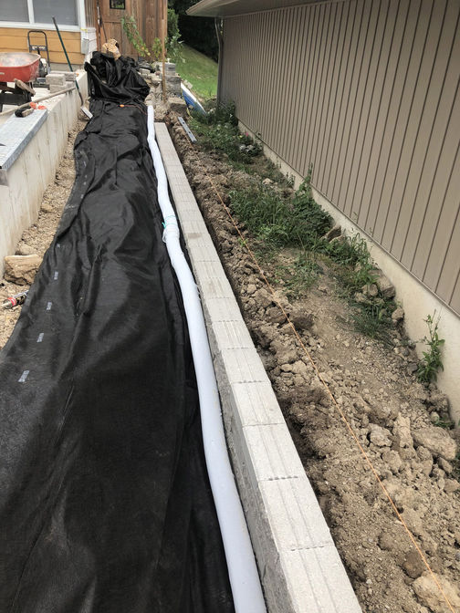 Retaining wall installation with weeping tile. A retaining wall cladding project by the London Ontario based O'Connor Stone & Landscape
