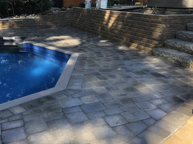 Engineered retaining wall, stone paver pool deck and stone steps. A retaining wall, paver deck and steps project by the London Ontario based O'Connor Stone & Landscape