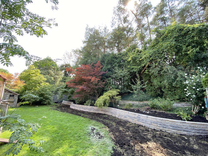 Sloped garden landscape with curved retaining walls. A project by the London based O'Connor Stone & Landscape
