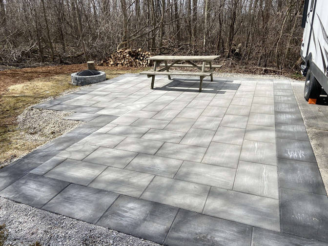 Paver deck with black border and a block stone firepit by the London based O'Connor Stone & Landscape