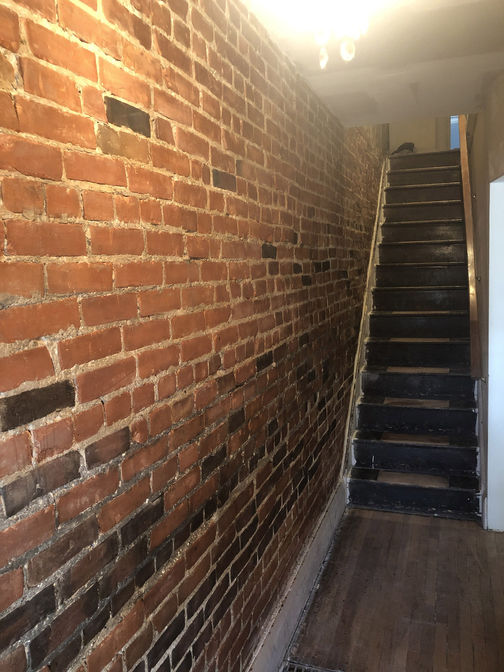 Interior brick wall exposure and restoration. A brick wall restoration project by O'Connor Stone & Landscape